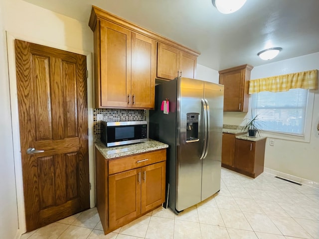 kitchen with stainless steel appliances, light stone counters, decorative backsplash, and light tile patterned flooring