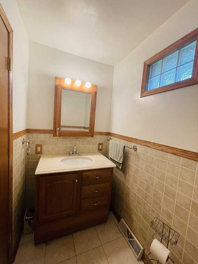 bathroom featuring visible vents, a wainscoted wall, tile patterned floors, vanity, and tile walls