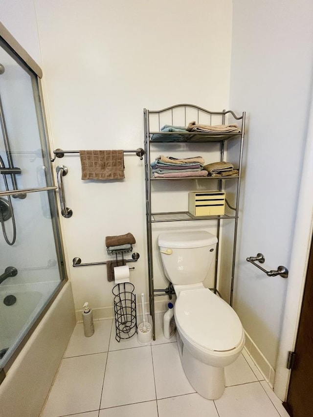 full bath with toilet, tile patterned flooring, baseboards, and combined bath / shower with glass door