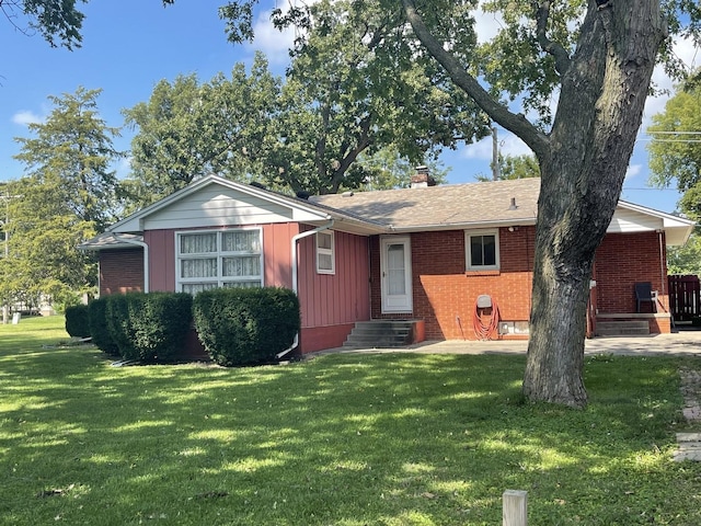 ranch-style home with brick siding, a chimney, board and batten siding, a front yard, and entry steps