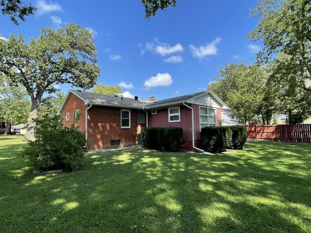 rear view of house with fence, a lawn, and brick siding