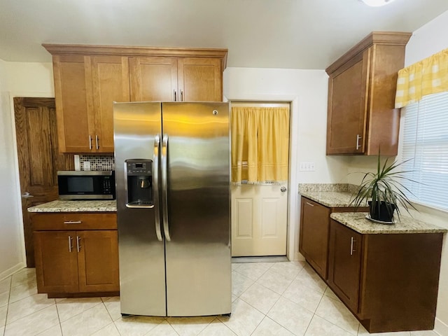 kitchen with light tile patterned floors, tasteful backsplash, appliances with stainless steel finishes, and light stone counters