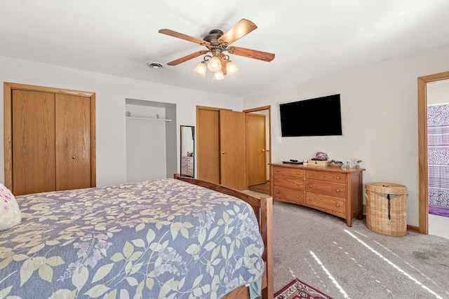 carpeted bedroom with ceiling fan and multiple closets