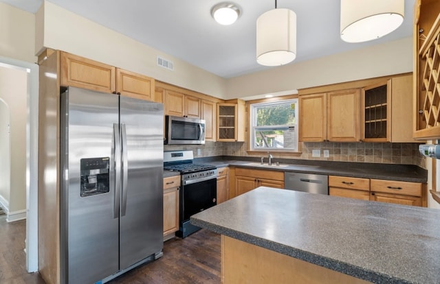 kitchen featuring appliances with stainless steel finishes, hanging light fixtures, dark wood-type flooring, and decorative backsplash