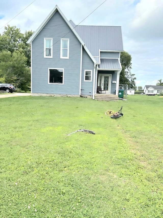 back of property with metal roof and a lawn