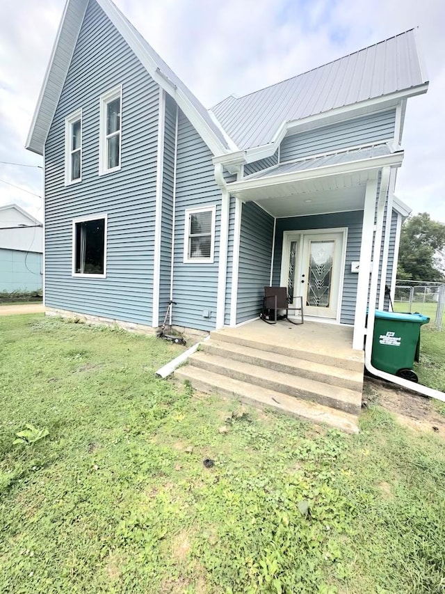 back of property featuring a porch, metal roof, and a yard