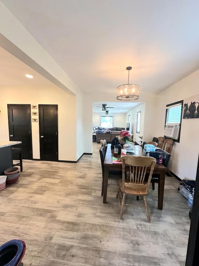 dining room featuring light wood-style flooring, baseboards, and ceiling fan with notable chandelier