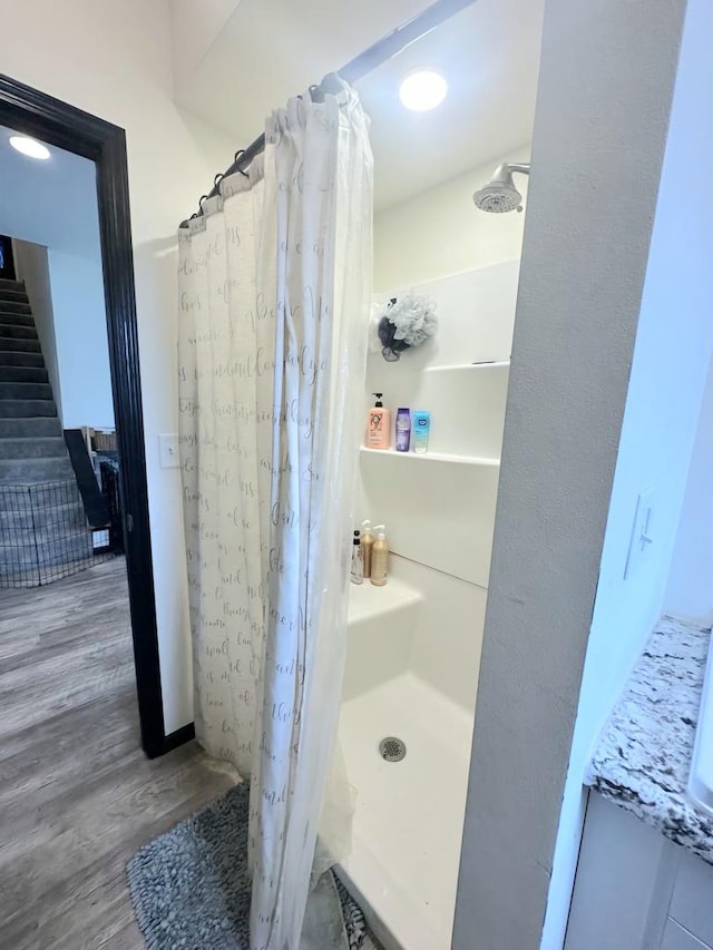 bathroom featuring wood finished floors and a shower stall