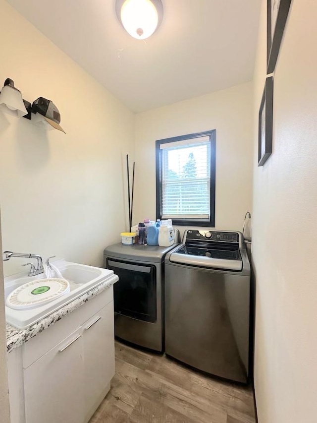 laundry area with laundry area, light wood-type flooring, a sink, and washer and dryer