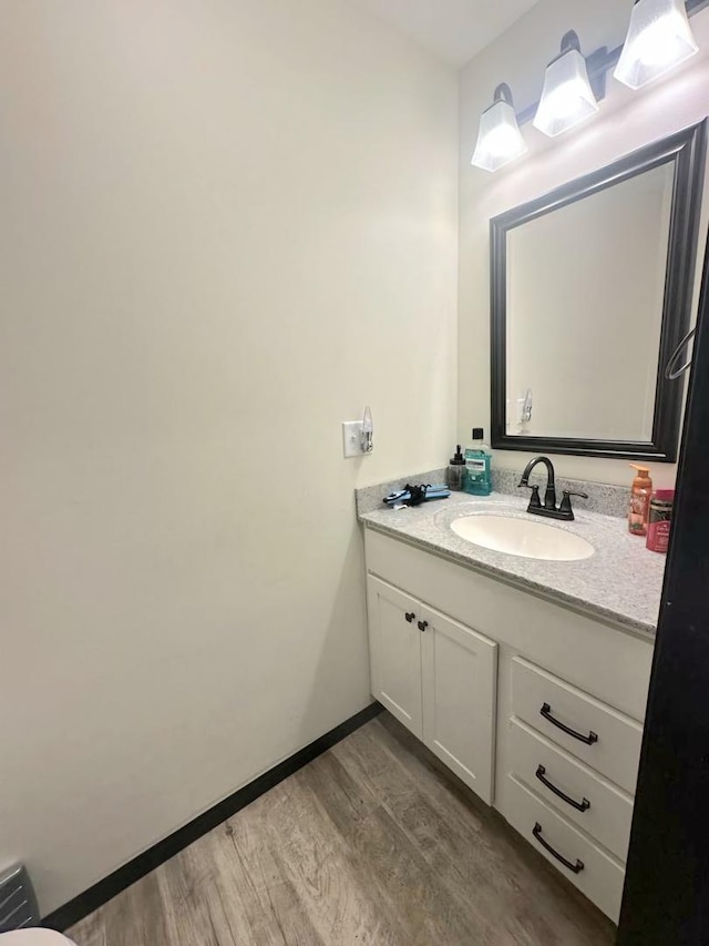 bathroom featuring baseboards, wood finished floors, and vanity