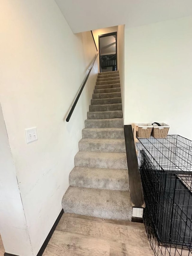 staircase featuring baseboards and wood finished floors