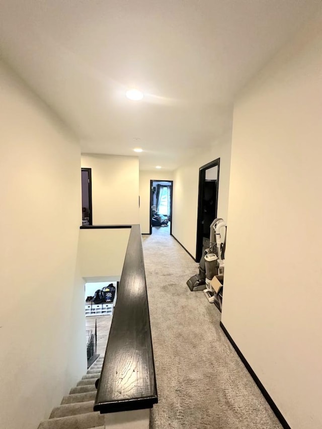 hallway with light colored carpet and an upstairs landing