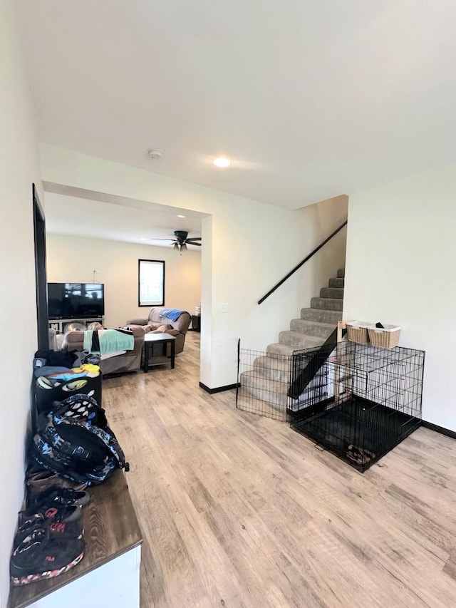 living area featuring ceiling fan, stairs, baseboards, and wood finished floors