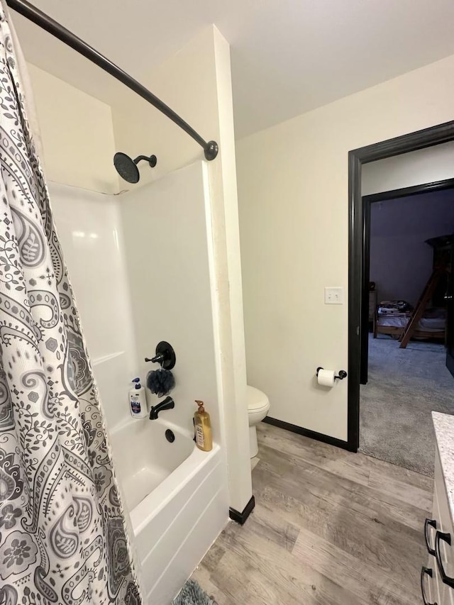 full bathroom featuring toilet, shower / tub combo, wood finished floors, vanity, and baseboards