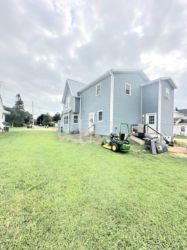 back of house with metal roof and a lawn