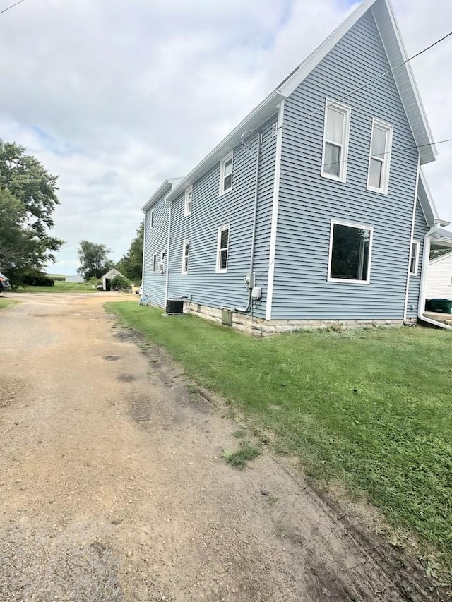 view of side of property featuring a yard and central AC