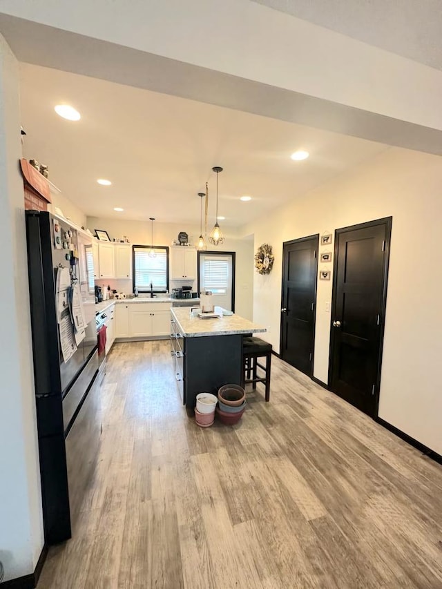 kitchen with light wood-style flooring, a center island, freestanding refrigerator, and white cabinets