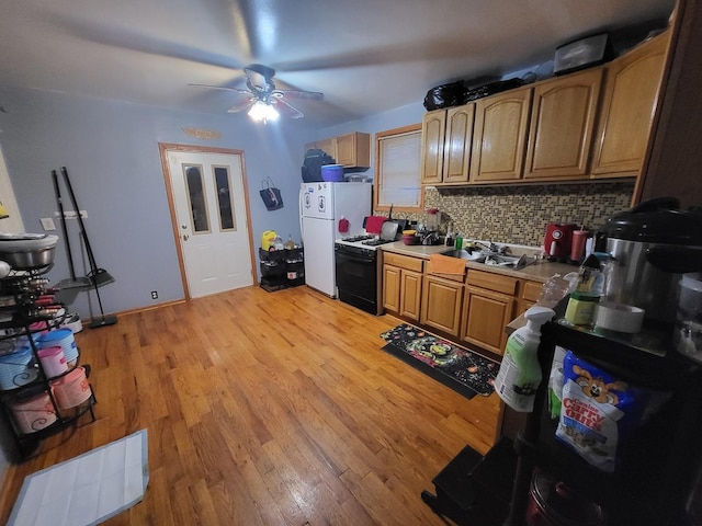 kitchen featuring decorative backsplash, black gas range oven, sink, light hardwood / wood-style flooring, and white fridge