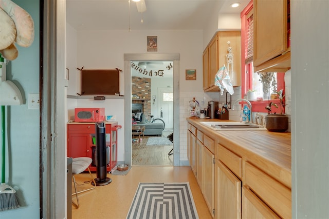 kitchen featuring sink, decorative backsplash, ceiling fan, light brown cabinets, and light hardwood / wood-style floors