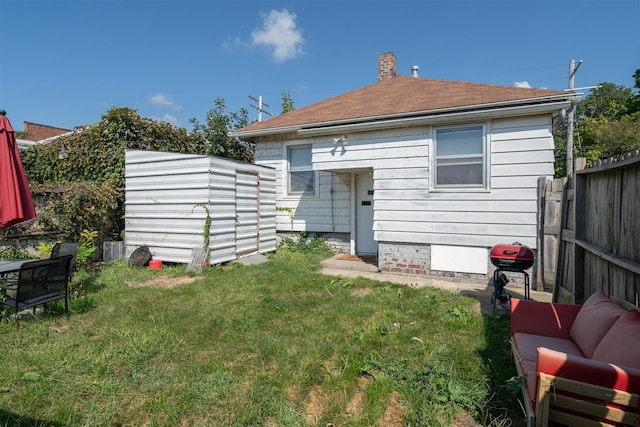 rear view of house with an outdoor living space, a lawn, and a storage unit