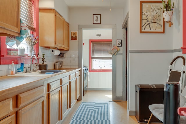 kitchen featuring stainless steel range oven, sink, light brown cabinets, and tasteful backsplash