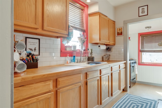 kitchen featuring light brown cabinetry, wood counters, sink, stainless steel range with gas cooktop, and tasteful backsplash