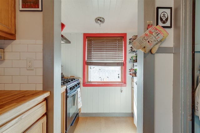 kitchen featuring range with gas stovetop, wooden walls, and extractor fan