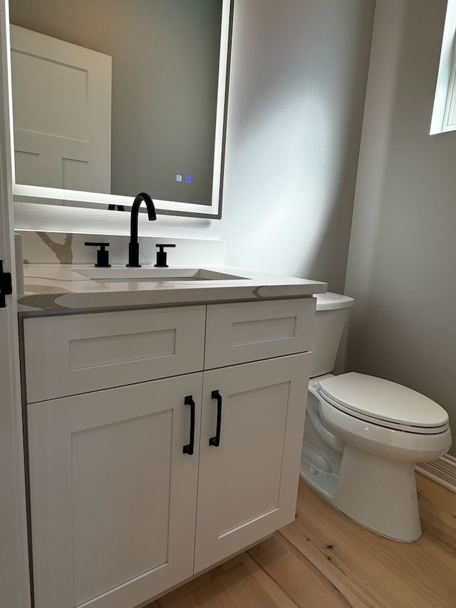 bathroom with vanity, toilet, and hardwood / wood-style flooring