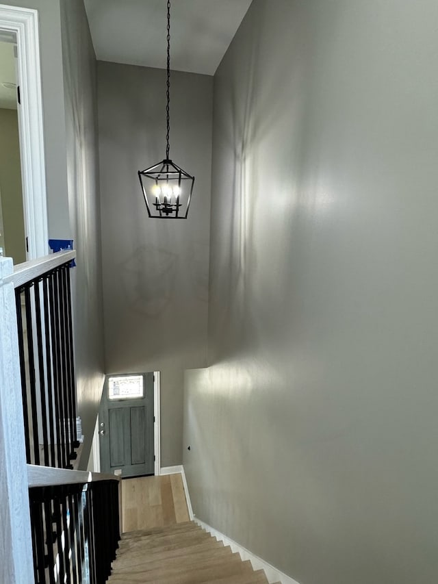 staircase featuring wood-type flooring and a chandelier