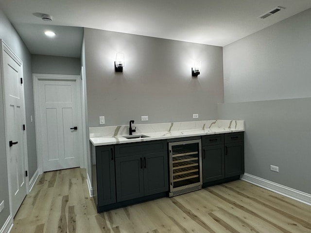 bar featuring gray cabinets, light hardwood / wood-style flooring, wine cooler, sink, and light stone countertops