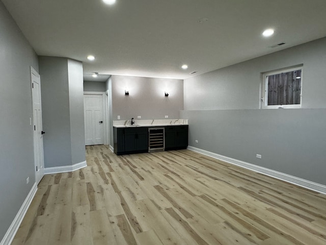 interior space with light wood-type flooring, wine cooler, and sink