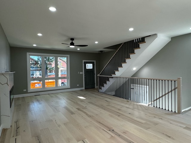 unfurnished living room with light wood-type flooring and ceiling fan