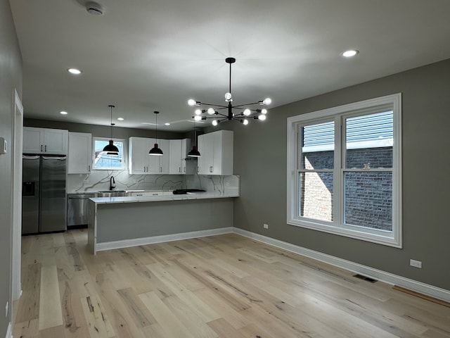 kitchen with pendant lighting, light hardwood / wood-style flooring, kitchen peninsula, stainless steel refrigerator with ice dispenser, and white cabinets