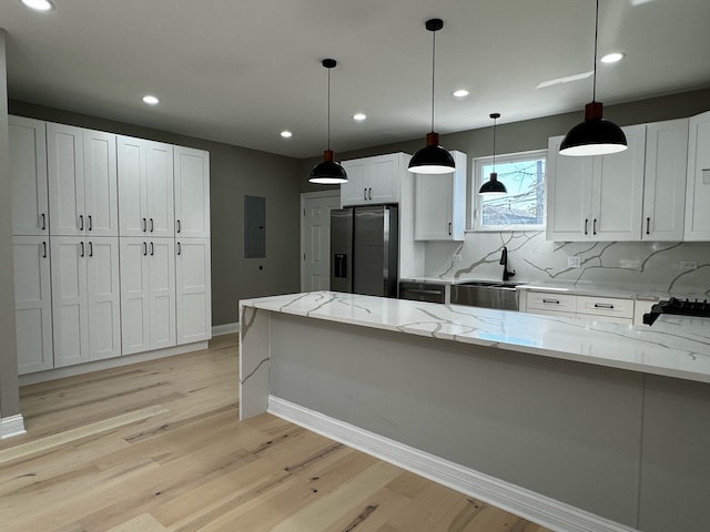 kitchen featuring stainless steel refrigerator with ice dispenser, light stone counters, decorative light fixtures, and light hardwood / wood-style floors