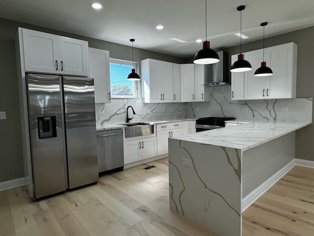 kitchen with backsplash, kitchen peninsula, sink, appliances with stainless steel finishes, and wall chimney range hood