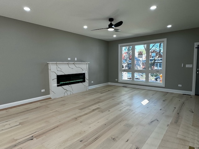 unfurnished living room featuring light hardwood / wood-style flooring, ceiling fan, and a fireplace