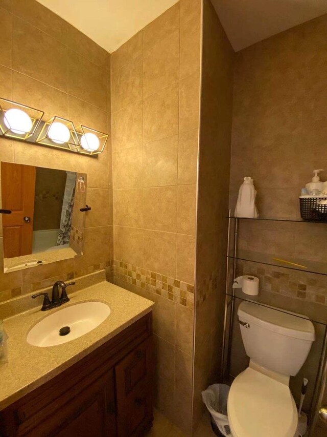 bathroom featuring vanity, toilet, tile walls, and tasteful backsplash