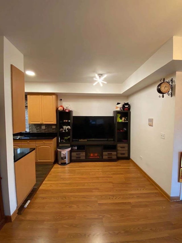 kitchen featuring wood-type flooring, backsplash, and light brown cabinetry