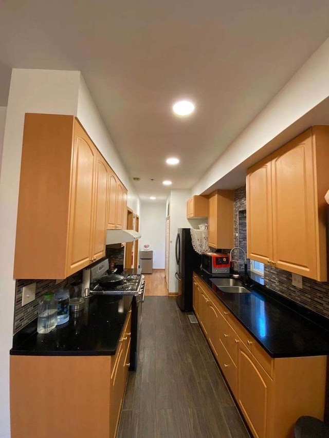 kitchen with stainless steel fridge, dark hardwood / wood-style flooring, gas range oven, tasteful backsplash, and sink