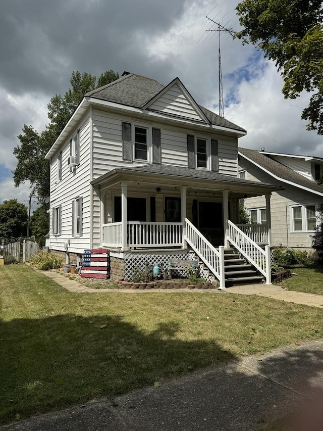 view of front of house with covered porch, a front lawn, and a shingled roof