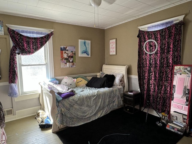 bedroom featuring ornamental molding, wood-type flooring, visible vents, and baseboards