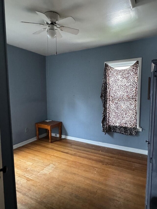 unfurnished room with a ceiling fan, baseboards, and wood finished floors