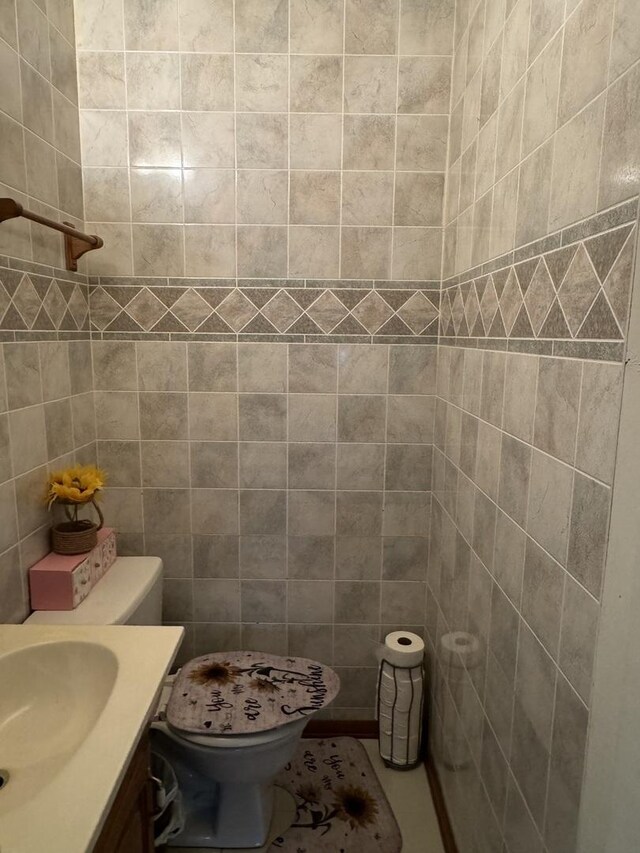 bathroom featuring vanity, toilet, and tile walls