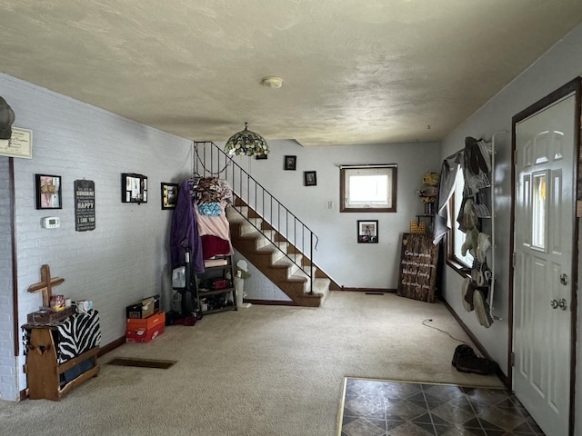 entryway featuring a textured ceiling, carpet floors, baseboards, stairway, and tile patterned floors