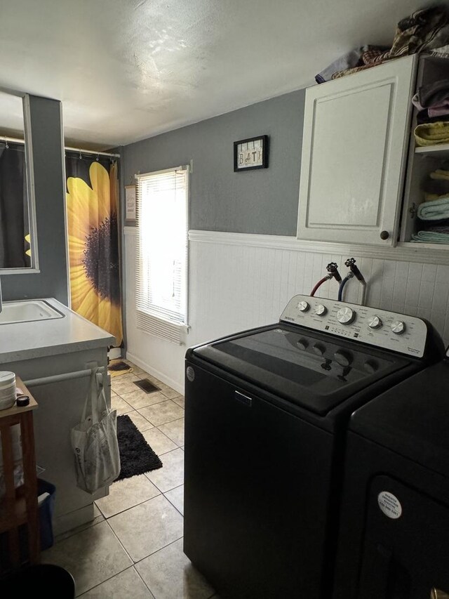 clothes washing area featuring light tile patterned floors, sink, and washer and dryer