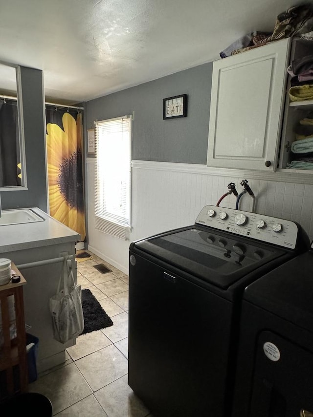 laundry room with visible vents, wainscoting, independent washer and dryer, a sink, and light tile patterned flooring