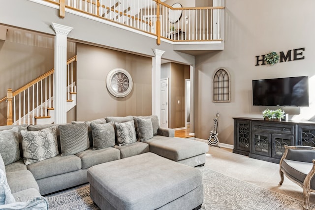 living room featuring carpet flooring, a high ceiling, and decorative columns