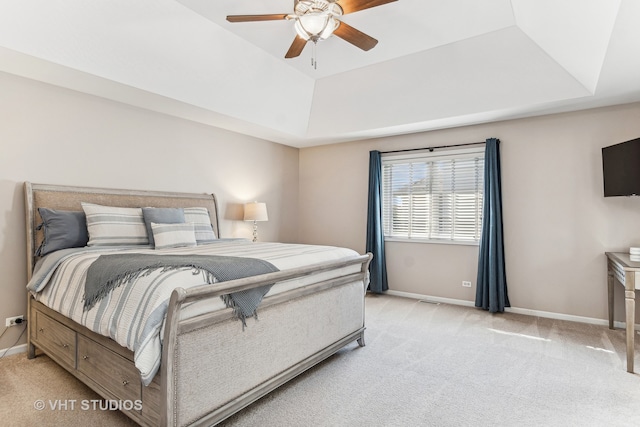 carpeted bedroom with a tray ceiling and ceiling fan