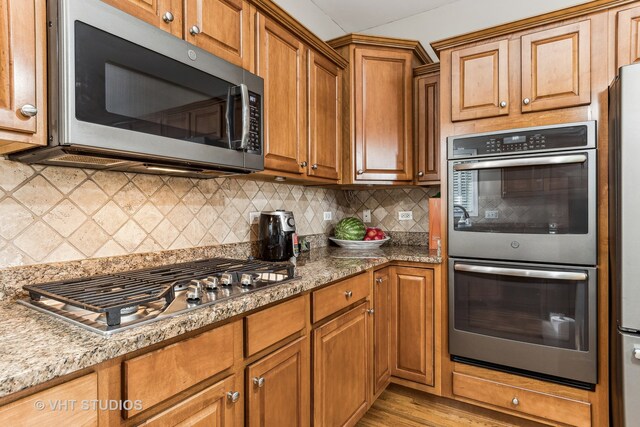 kitchen with appliances with stainless steel finishes, decorative backsplash, and stone counters