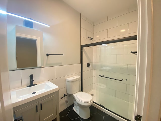 bathroom with an enclosed shower, tile patterned floors, toilet, tile walls, and vanity